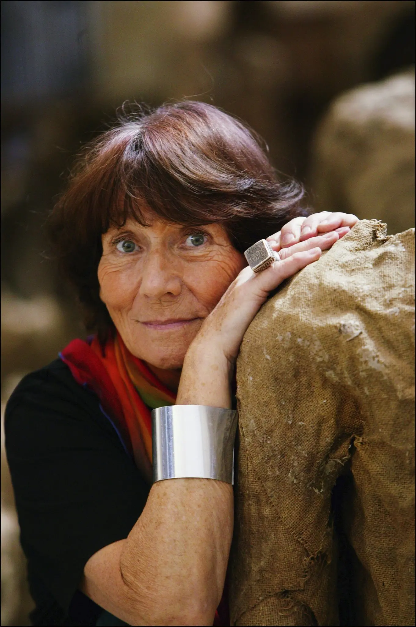 Magdalena Abakanowicz, the renowned Polish artist, leaning on one of her burlap sculptures. Her expressive gaze and textured artwork highlight her deep connection to material and form, which defined her legacy in contemporary sculpture and textile art.