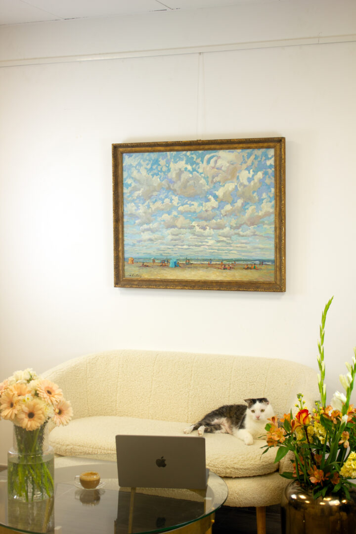 André Hambourg's 'Temps Doux à Deauville en Août' hanging in a modern interior, displayed above a sofa with a cat resting nearby.