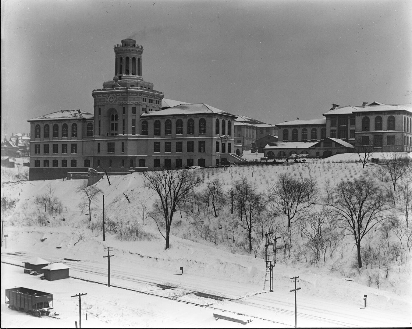 Historic black-and-white photo of the Carnegie Institute of Technology in Pittsburgh, 1913, featuring a large building with a central tower, surrounded by snow-covered grounds and leafless trees.