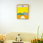 The painting "Pathway to the Sun" hanging on a white wall above a modern sofa, presenting a contemporary living space setting.