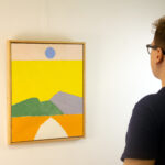 A viewer admiring Etel Adnan’s "Pathway to the Sun," highlighting the painting’s vibrant colors and bold composition.