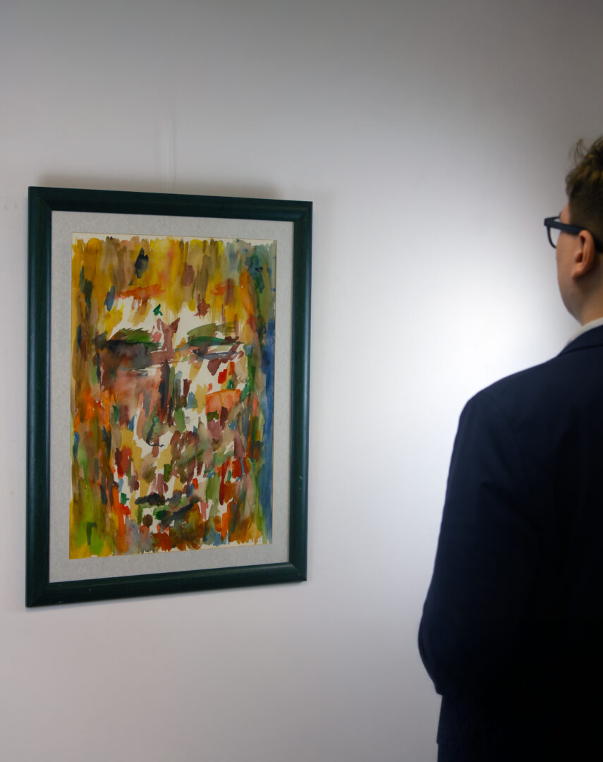 A visitor observes Marwan Kassab-Bachi’s painting Kopf (1995) in a gallery setting, showcasing the expressive abstraction of his signature portrait style.