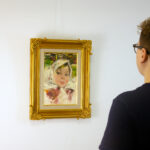 A viewer admiring Girl with White Scarf by Nicolai Fechin in an exhibition space, illustrating the artwork’s scale and impact within a room.