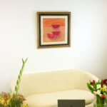 "Sandías, 1972" by Rufino Tamayo displayed on a white wall in an interior setting with a modern sofa, laptop, and flowers.