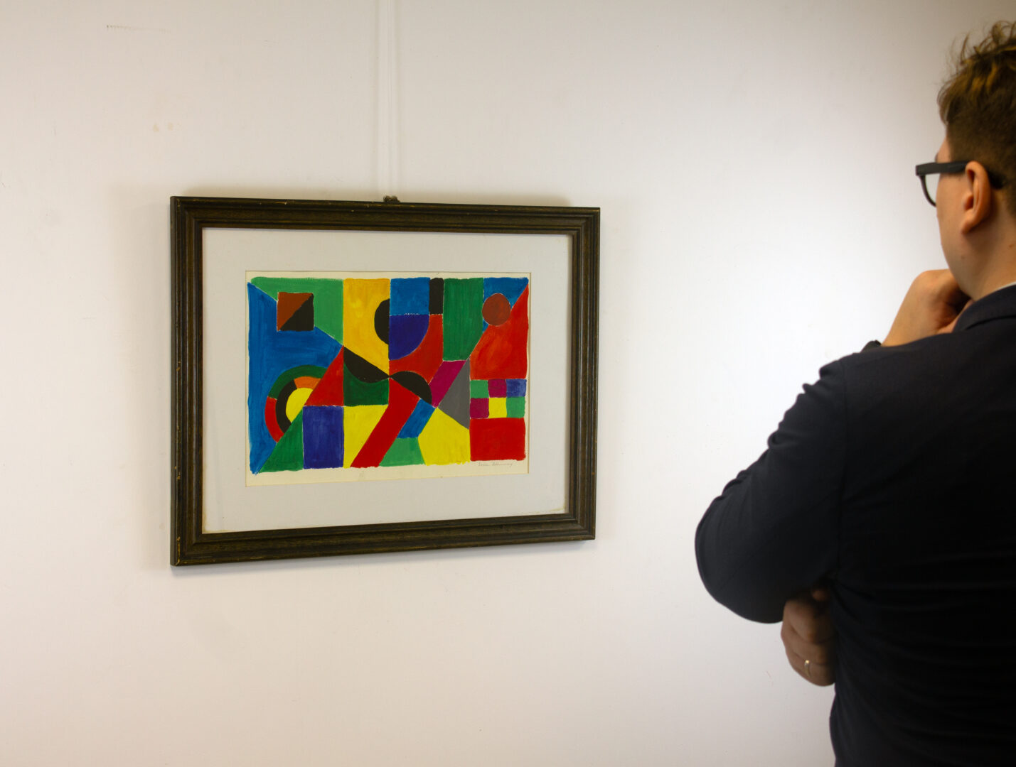 A person in a dark suit observing Rythme Couleur (1955) by Sonia Delaunay, illustrating scale and gallery presentation.