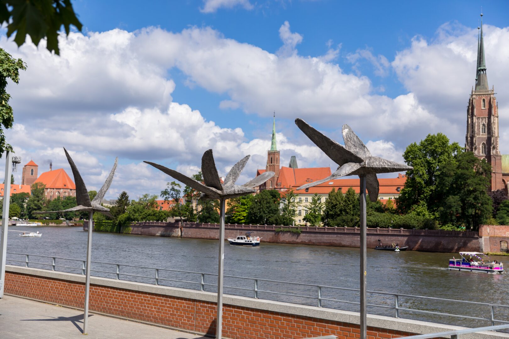 Sculpture "Birds" by Magdalena Abakanowicz on the boulevard along the Odra River in Wrocław, Poland, with Ostrów Tumski’s historic architecture in the background.