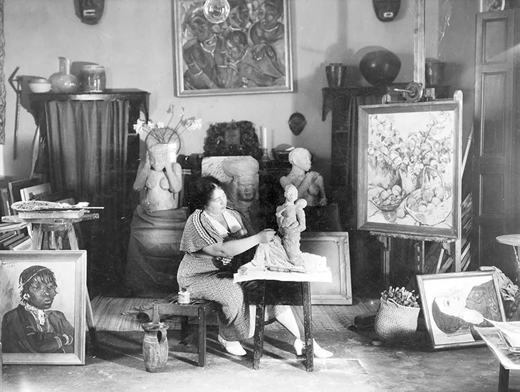 Irma Stern in her Cape Town studio, surrounded by African art and canvases. | Aurora & Athena Auction House Irma Stern in her Cape Town studio, surrounded by African art and canvases.