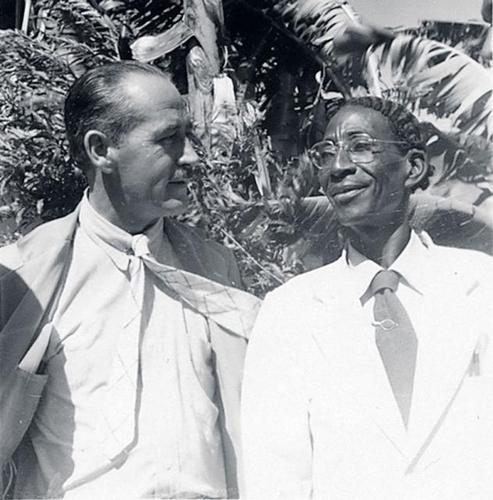 Photograph of Hector Hyppolite (right) in 1948, alongside art dealer DeWitt Peters (left). The self-taught artist often painted with improvised tools like chicken feather brushes, guided by Vodou spirits (as legend tells). Hyppolite’s short career bridged Haitian folk culture with the international art world | Aurora & Athena Auction House Photograph of Hector Hyppolite (right) in 1948, alongside art dealer DeWitt Peters (left). The self-taught artist often painted with improvised tools like chicken feather brushes, guided by Vodou spirits (as legend tells). Hyppolite’s short career bridged Haitian folk culture with the international art world